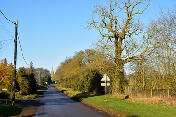 Local road leading to a small English village under a clear blue sky