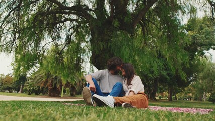 Happy smiling couple talking while sitting on blanket in park