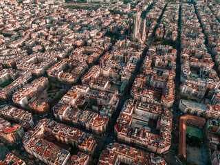Obraz premium Aerial view of Barcelona City Skyline and Sagrada Familia Cathedral at sunset. Eixample residential famous urban grid. Cityscape with typical urban octagon blocks