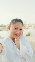 Young woman taking selfie on mobile phone on seascape background