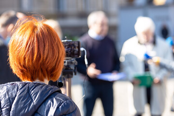 Filming whistleblower holding confidential document at media event or news conference with smartphone. Mobile or citizen journalism concept.