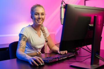 Smiling e-sport gamer girl vlogging and plays online video game on PC