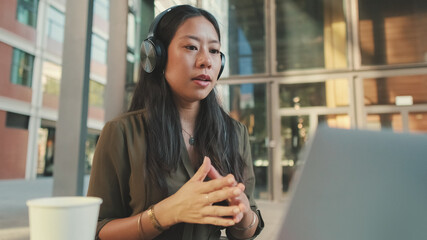 Young woman freelancer in headphones holding video conference on laptop