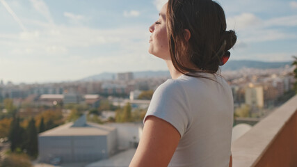 Young woman enjoying beautiful view while standing on the balcony