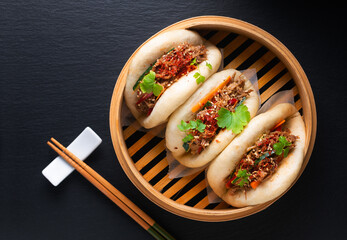 Food concept Homemade organic Pulled Beef Bao Buns or Gua Bao in bamboo stream tray on black...