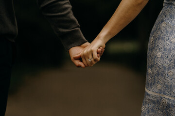 Engaged couple holding hands together walking in the park