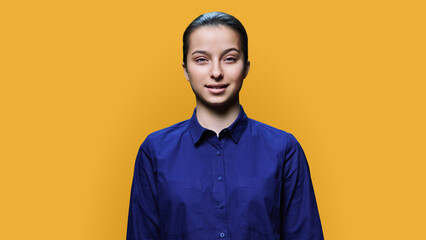 Obraz premium Portrait of smiling teenage girl 15, 16 years old on yellow background