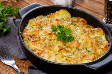 Obraz na płótnie Canvas Potato casserole with cheese and parsley on wooden table. French cuisine, close up