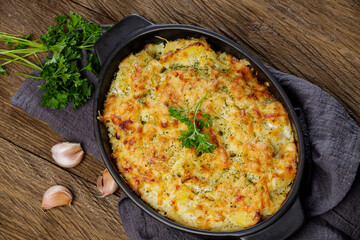Potato casserole with cheese and parsley on wooden table. French cuisine, top view