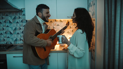 Couple Sing And Song With Guitar In Kitchen to her girlfriend for valentines day
