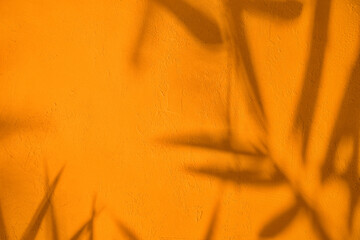 Abstract tree leaves shadows on orange concrete wall texture with roughness and irregularities....