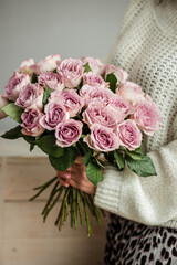 a woman holds a bunch of light roses in her hands