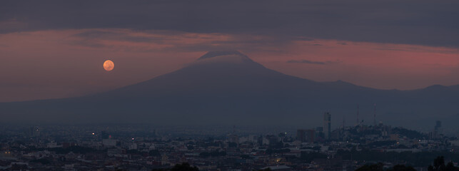 Panorama de un amanecer nublado con luna llena y el Popocatépetl en Puebla