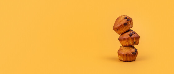 3 Muffins de chocolate, uno encima de otro, en fondo banner largo simple minimalista de color Amarillo 