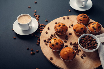 Taza de café, desayuno con muffins de chocolate, en una bandeja de madera, granos de café en fondo azul oscuro