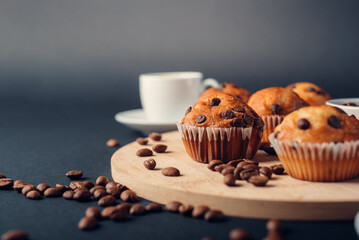 Muffins de chocolate, con taza de café en una bandeja de madera, granos de café en fondo azul...