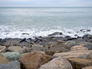 resort in winter. The rocky shore is washed by the waves in cloudy weather. Black Sea coast. The coast of Batumi. Nature in shades of grey.  boring landscape