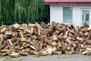 A pile of firewood for heating in winter in the yard of the farm