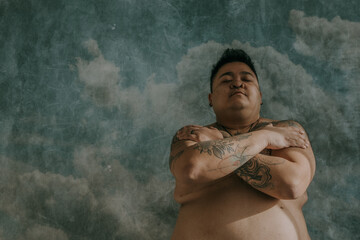 portrait of a plus size non-binary asian person with arms across chest and eyes closed