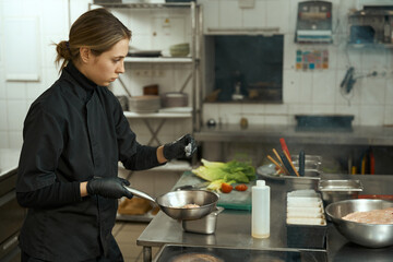 Woman chef fries meat in a small frying pan