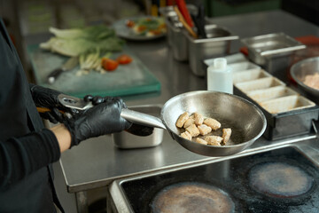 Chef cooks meat in a frying pan in oil