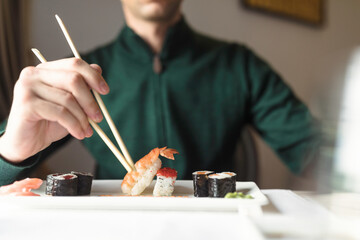 Young couple sharing a plate of sushi rolls, as they enjoy a romantic night out, experiencing the flavors and ambiance of a traditional Japanese restaurant