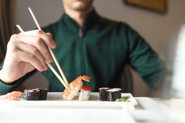 Fototapeta premium Young couple sharing a plate of sushi rolls, as they enjoy a romantic night out, experiencing the flavors and ambiance of a traditional Japanese restaurant
