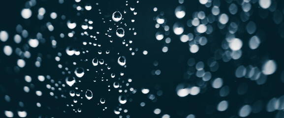 Atmospheric minimal monochrome backdrop with rain droplets on glass. Wet window with rainy drops and dirt spots closeup. Blurry minimalist background of dirty window glass with raindrops close up.