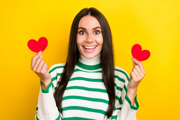 Photo of funky excited lady dressed striped pullover holding two little hearts isolated yellow color background
