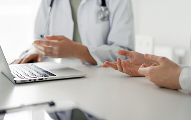 Fototapeta premium Doctor and patient discussing current health examination while sitting at the desk in clinic office, closeup. Perfect medical service and medicine concept