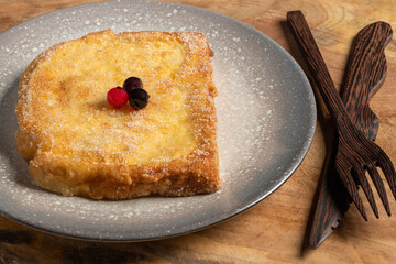 (Torrijas) Fried bread soaked in milk flavored with vanilla, cinnamon, lemon and egg with chocolate on a wooden background.Typical Easter sweet. Concept of traditional festive cuisine.