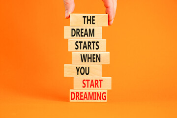 Start dreaming symbol. Concept words The dream starts when you start dreaming on wooden blocks. Beautiful orange background. Copy space. Businessman hand. Motivational business start dreaming concept.