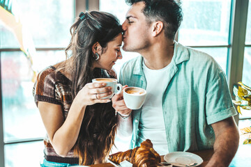 Happy couple enjoying breakfast drinking coffee at bar cafeteria - Life style concept with guy and...