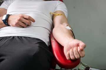 Detail with hand of a blood donor donating blood in a hospital - 570404949