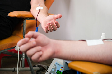 Detail with hand of a blood donor donating blood in a hospital