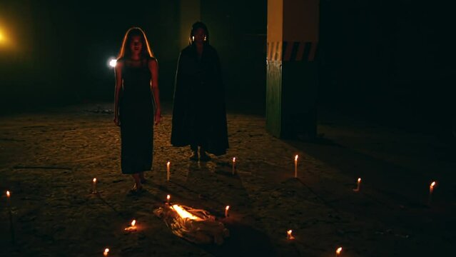 a group of satanic cultists walk amidst an altar of pentagrams and lit candles during a ritual