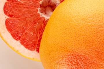 Two halves of a ripe grapefruit on a white ceramic plate, macro, top view.