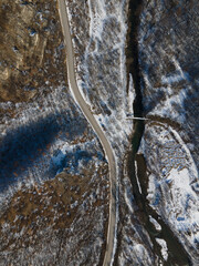 Aerial drone view on the road trough the hill and mountain in winter day covered with snow with rock and trees and river in Serbia