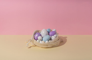 Composition with easter eggs in crochet organic shopping bag against two colors pastel background. Creative easter holiday concept.