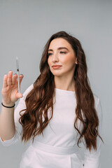young woman doctor in a white coat holds an insulin syringe in her hand. Girl cosmetologist preparing to make an injection of hyaluronic acid in a cosmetology clinic