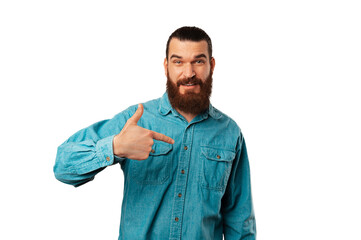 Fototapeta premium Bearded man is pointing at himself and asking if you were looking for him over white background.