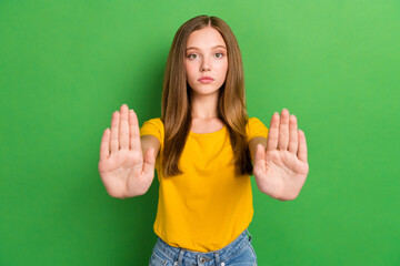 Photo of serious calm teenager girl wear yellow t-shirt showing stop palm no restriction against...