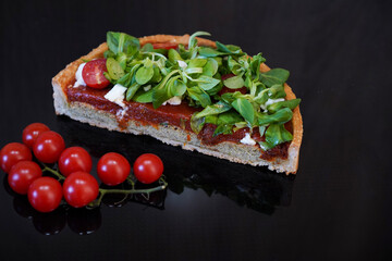 Cake slice of vegetables lying on the black mirror surface. Healthy cooking concept