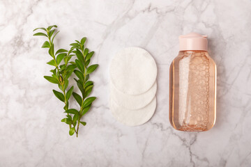 Fototapeta na wymiar Micellar cleansing water and cotton pads on a marble background. Facial cleansing or makeup remover cosmetic bottle in bathroom. Skin care concepts. Cleansing the face of makeup and skin sebum.