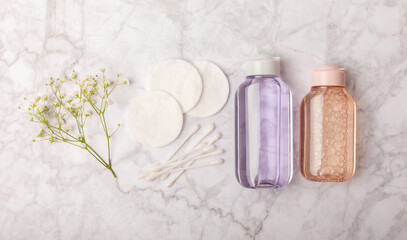 Micellar cleansing water and cotton pads on a marble background. Facial cleansing or makeup remover cosmetic bottle in bathroom. Skin care concepts. Cleansing the face of makeup and skin sebum.