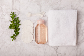 Fototapeta na wymiar Micellar cleansing water and cotton pads on a marble background. Facial cleansing or makeup remover cosmetic bottle in bathroom. Skin care concepts. Cleansing the face of makeup and skin sebum.