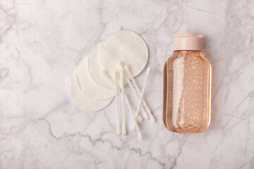 Micellar cleansing water and cotton pads on a marble background. Facial cleansing or makeup remover cosmetic bottle in bathroom. Skin care concepts. Cleansing the face of makeup and skin sebum.