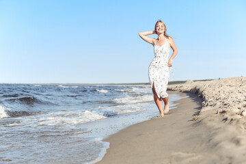 Happy blonde beautiful woman having fun on ocean beach while dancing in waves