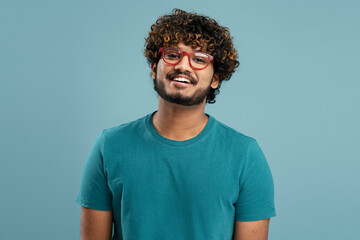 Portrait of confident smiling Indian student wearing green t shirt and stylish eyeglasses looking at camera isolated on background. Education concept