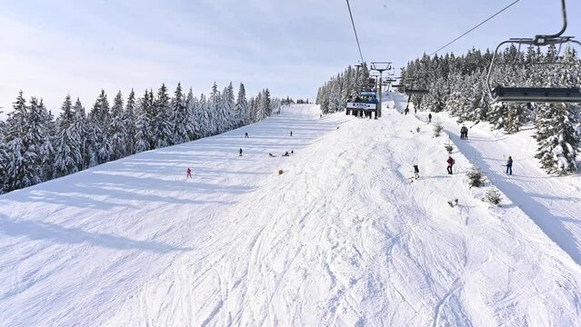 SPINDLERUV MLYN, CZECH REPUBLIC - 05.02.2023: Cable car and skiers on the top of the mountain. In the background is Mount Medvedin. Mountain Krkonose, popular Czech ski resort